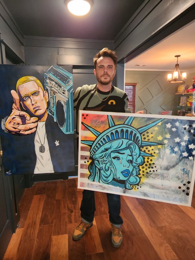 Beau Pendergraft holding his Eminem and Statue of Liberty pop-art paintings