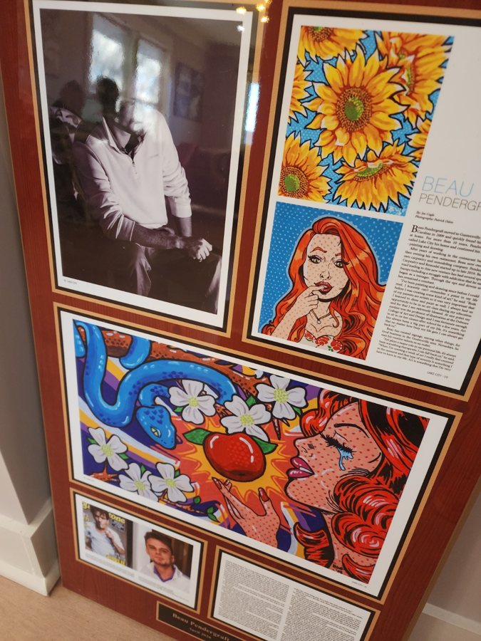 Framed magazine feature on Beau Pendergraft displayed alongside his sunflower and pop-art paintings