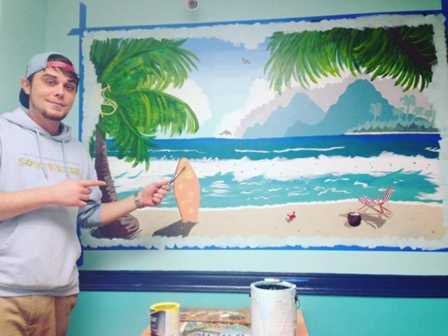 Beau Pendergraft painting a large-scale tropical beach mural