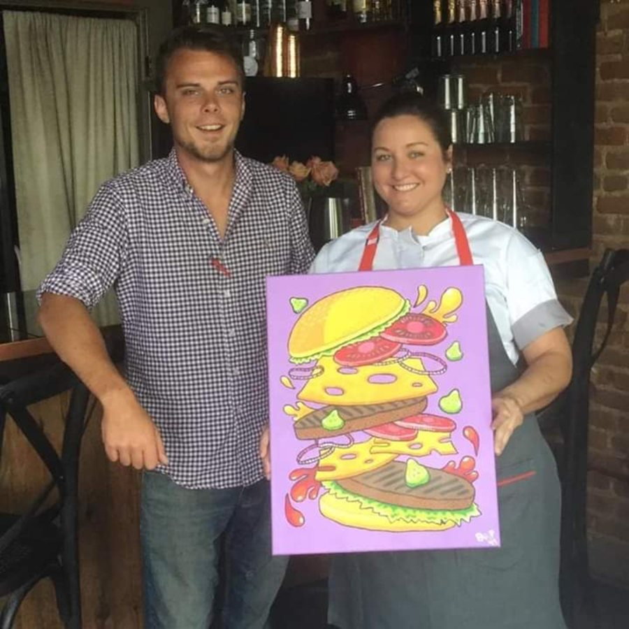 Beau Pendergraft with a restaurant client holding a commissioned burger painting